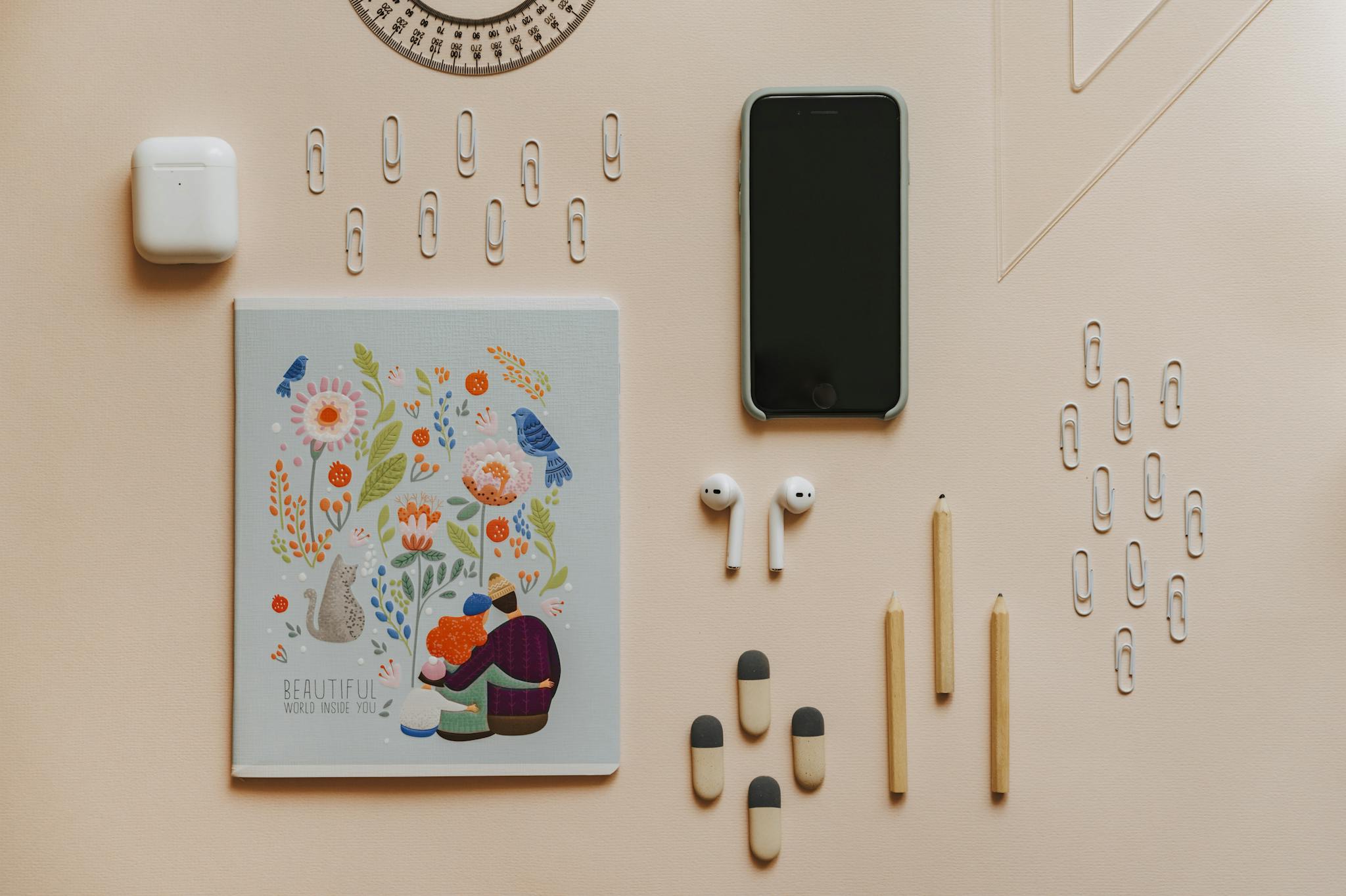 A neatly arranged flat lay of stationery items and gadgets on a pastel surface.