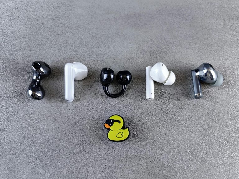 Stylish wireless earbuds creatively arranged with a playful rubber duck on gray background.